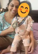 Harneet smiling at home, holding up her Show-Up Champion medal.