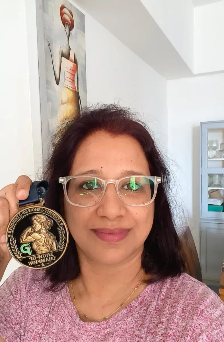 Kavita holding her Show-Up Champion medal up beside her face.