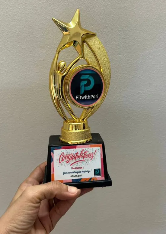 Aditi’s hand holding her gold FitwithPari consistency trophy