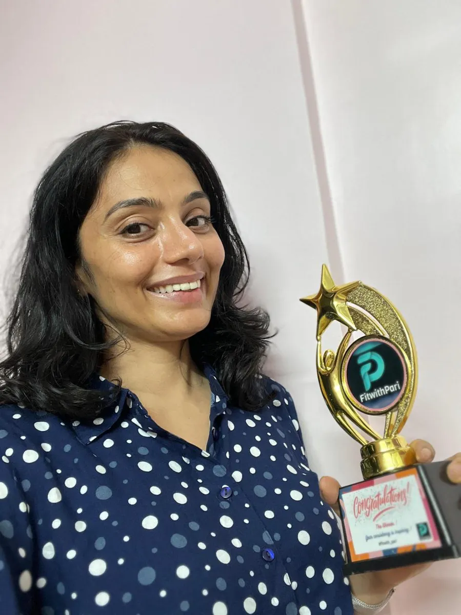 FitwithPari member holding an earlier recognition trophy