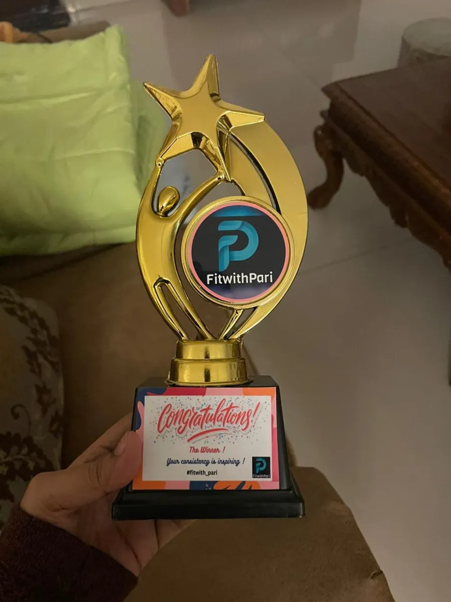 An earlier FitwithPari recognition trophy held up in a member’s hand