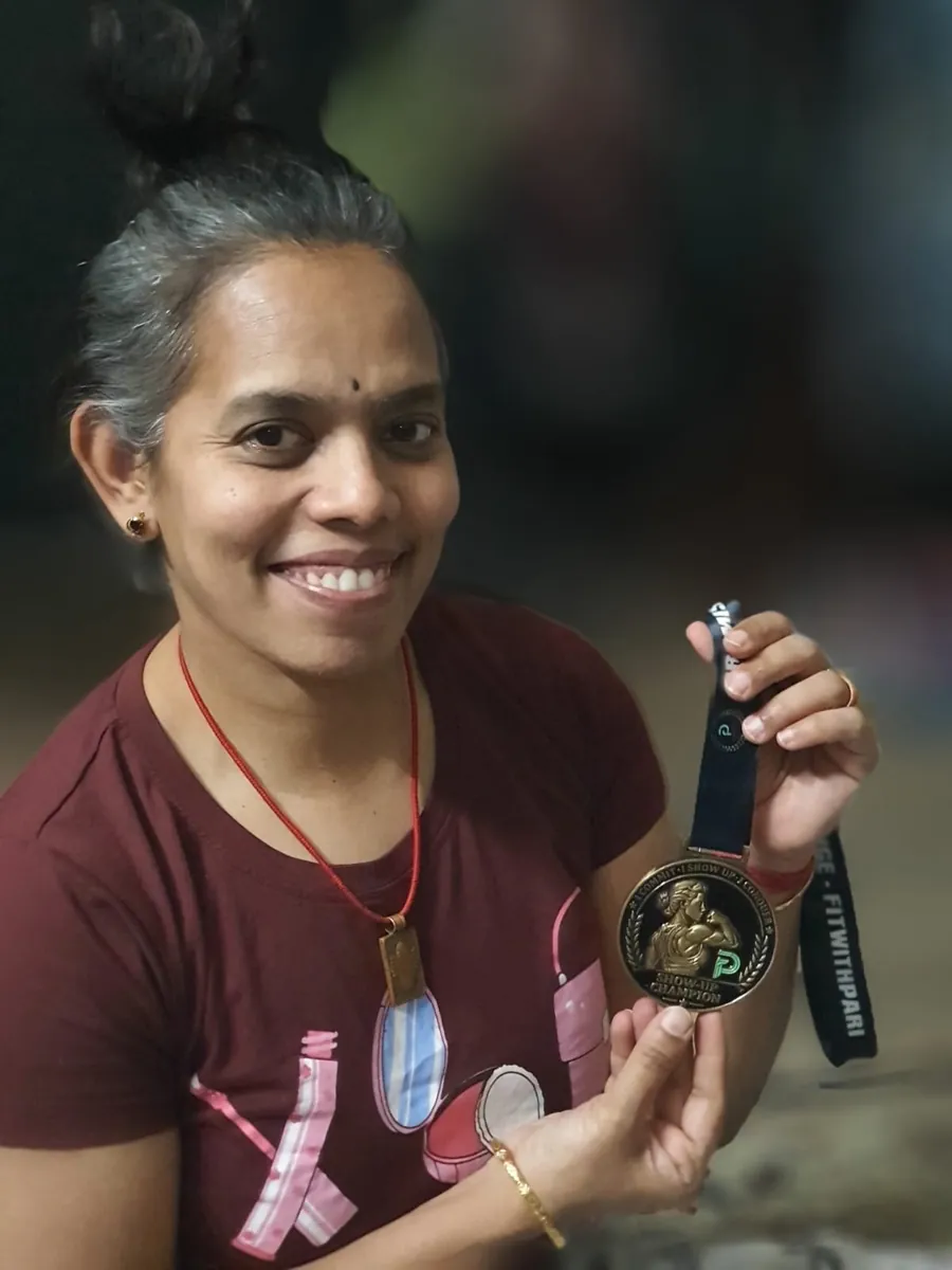 Arti smiling, holding up her Show-Up Champion medal on its lanyard.