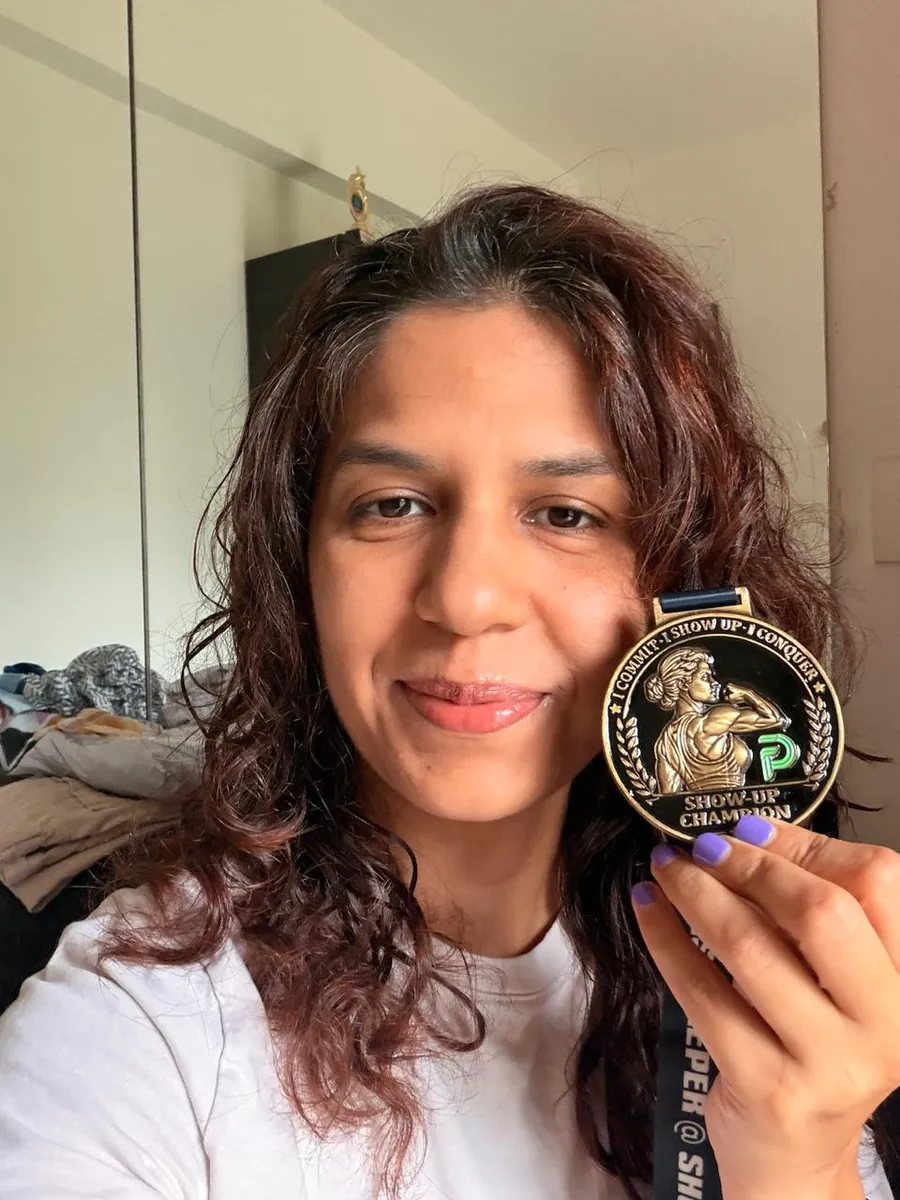 Heena holding her Show-Up Champion medal up beside her face.
