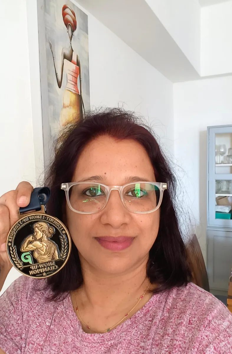 Kavita holding her Show-Up Champion medal up beside her face.