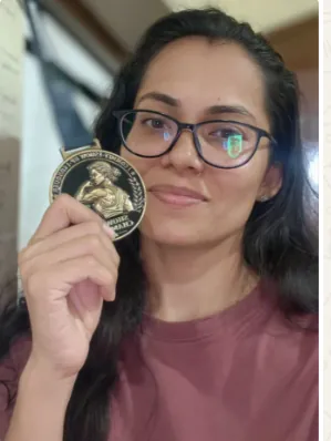 Suparna holding her Show-Up Champion medal up beside her face.