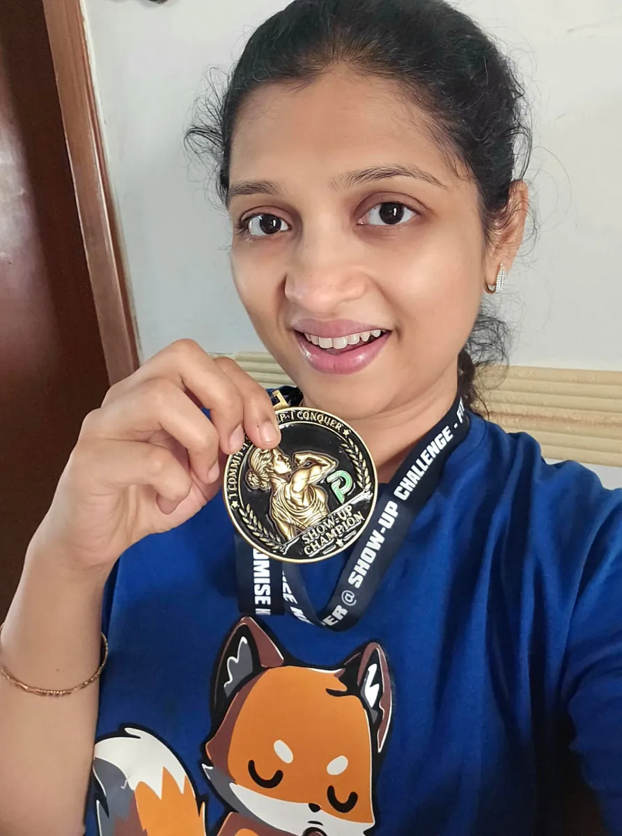 Swarna wearing her Show-Up Champion medal on its lanyard and holding it up to the camera.